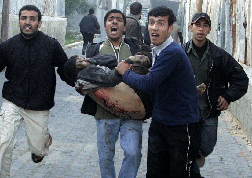 A wounded Palestinian is carried near a United Nations school in Jabalya following an Israeli attack that killed dozens